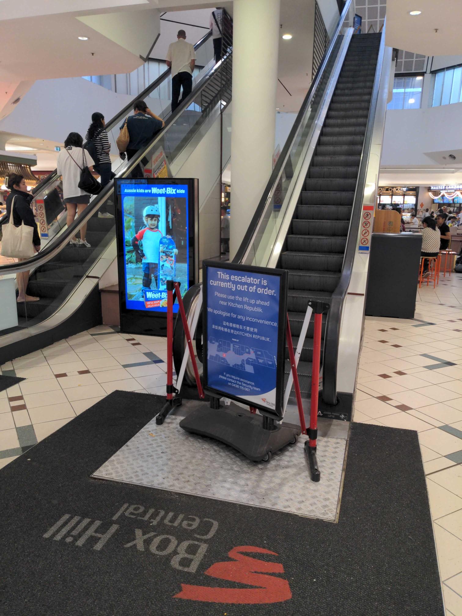 Photo of the down escalator at Box Hill Bus Station with a sign in front saying that it is broken.